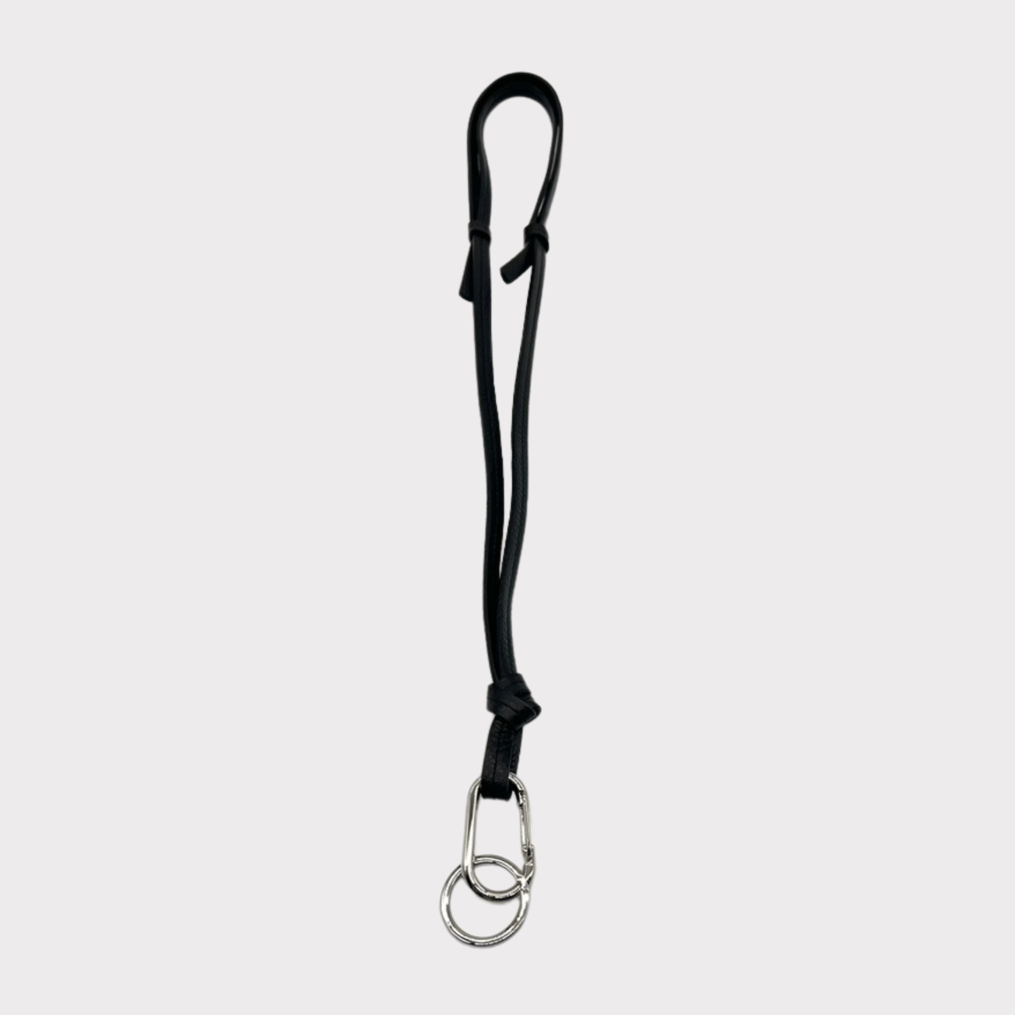 Hochwertiges schwarzes Leder-Schlüsselband, das auch als Crossbody-Tragegurt verwendet werden kann. Es ist mit einem silbernen Karabinerhaken und Schlüsselring ausgestattet, an dem ein Mini-Wallet, Schlüssel und Handy sicher befestigt werden können. Das stilvolle und praktische Accessoire ist ideal für unterwegs.